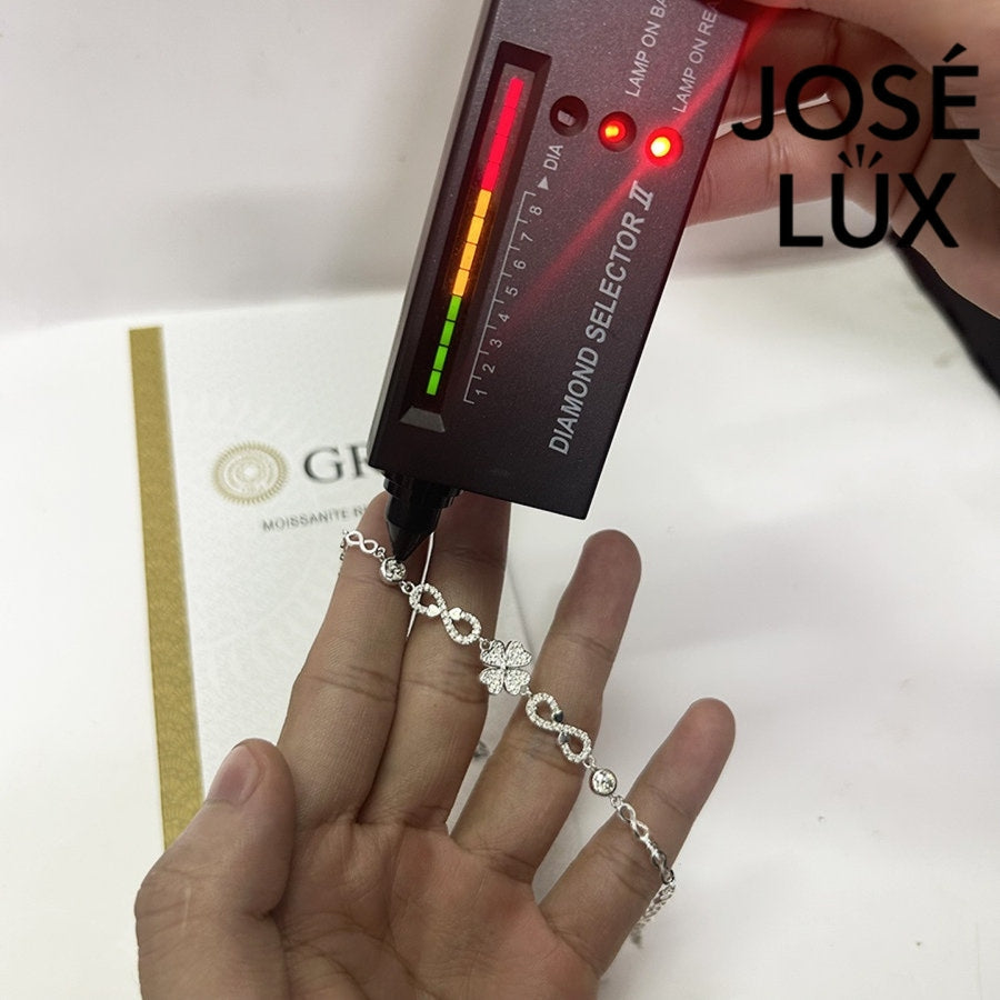 Infinity link moissanite bracelet in sterling silver showcases clover centerpiece with two brilliant stones totaling 0.68 carats on symbolic endless chain design.