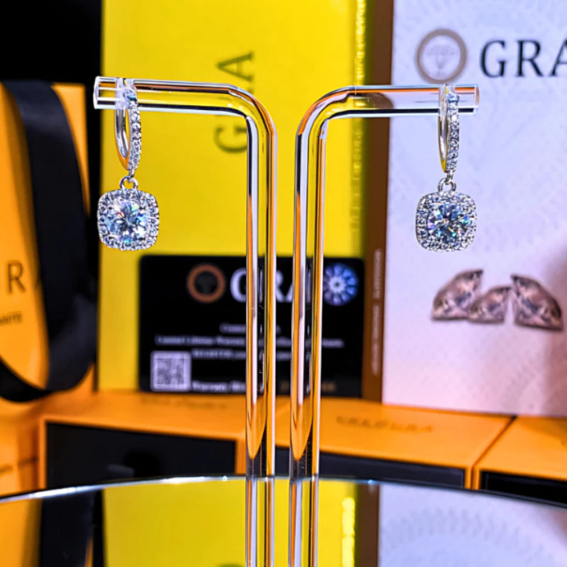 Elegant cushion-cut moissanite with sparkling halo setting in sterling silver. Graceful drop design adds sophisticated movement and brilliant fire for timeless everyday elegance.