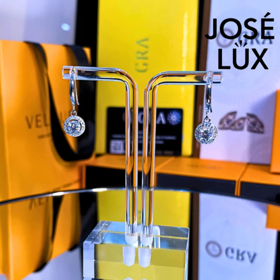 Elegant round moissanite with sparkling halo setting in sterling silver. Graceful dangle design adds beautiful movement and brilliant fire for sophisticated everyday wear.