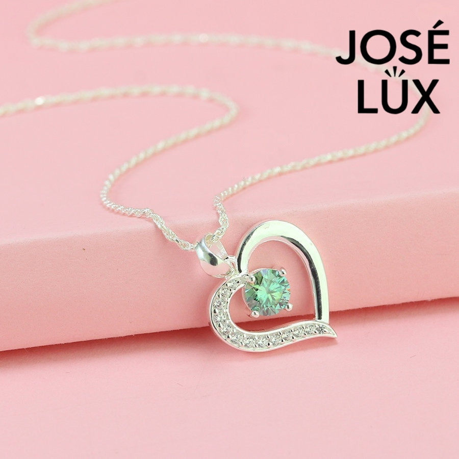 Enchanting 0.6ct round green moissanite open heart pendant features vibrant colored stone with pavé accents, romantically crafted in polished sterling silver.