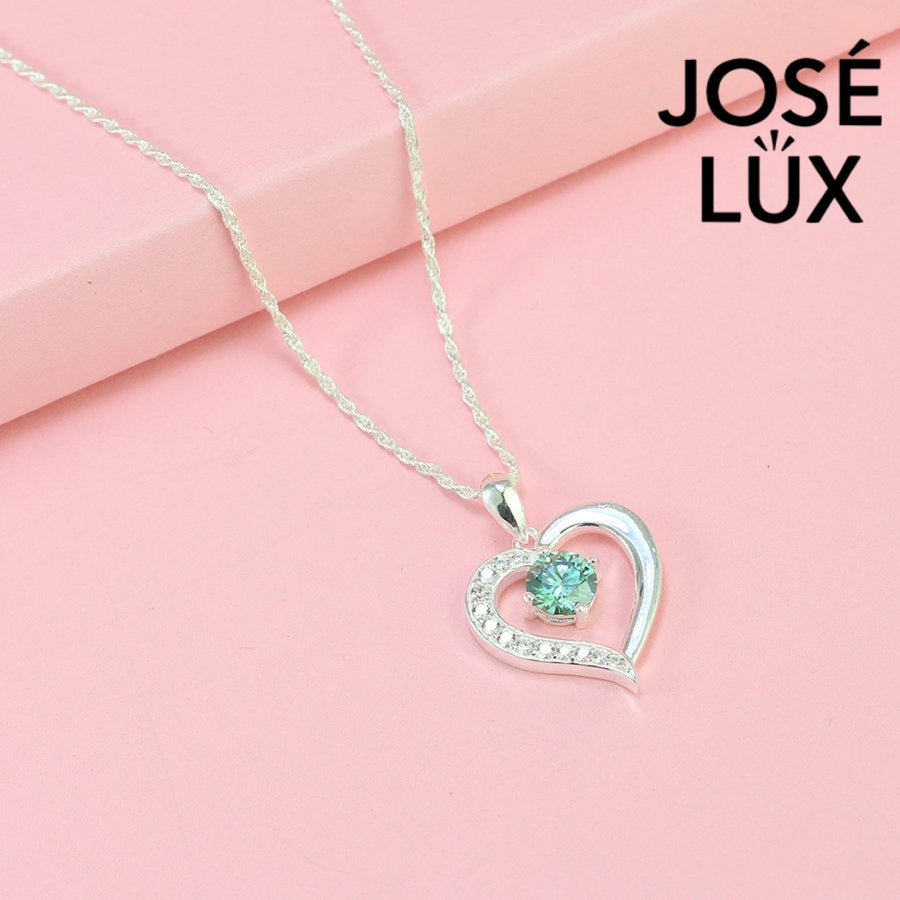 Enchanting 0.6ct round green moissanite open heart pendant features vibrant colored stone with pavé accents, romantically crafted in polished sterling silver.