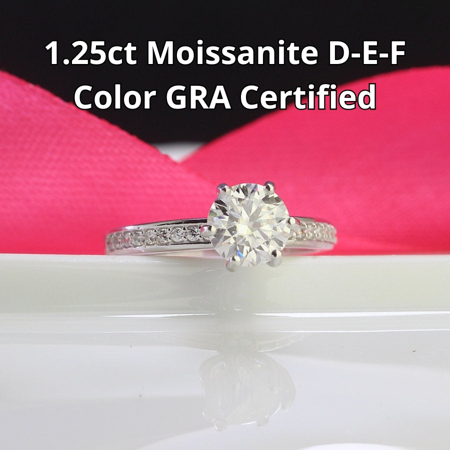 Classic solitaire design featuring brilliant 1.25ct moissanite and complementary accent stones beautifully showcased in sterling silver setting.