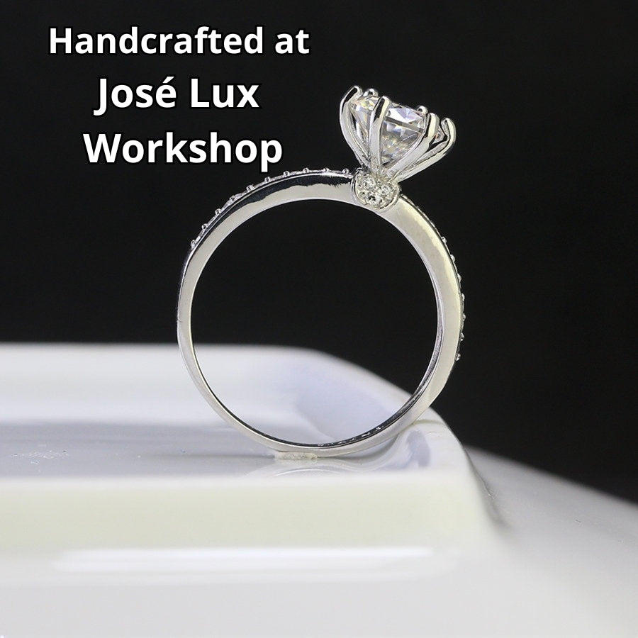 Classic solitaire design featuring brilliant 1.25ct moissanite and complementary accent stones beautifully showcased in sterling silver setting.