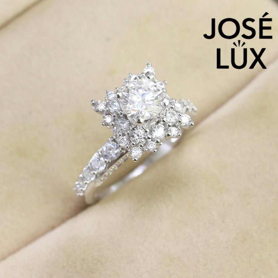Vintage-inspired art deco design features brilliant round moissanite surrounded by sparkling halo accents on a delicate pavé band.