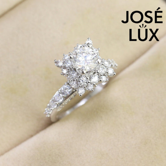 Vintage-inspired art deco design features brilliant round moissanite surrounded by sparkling halo accents on a delicate pavé band.