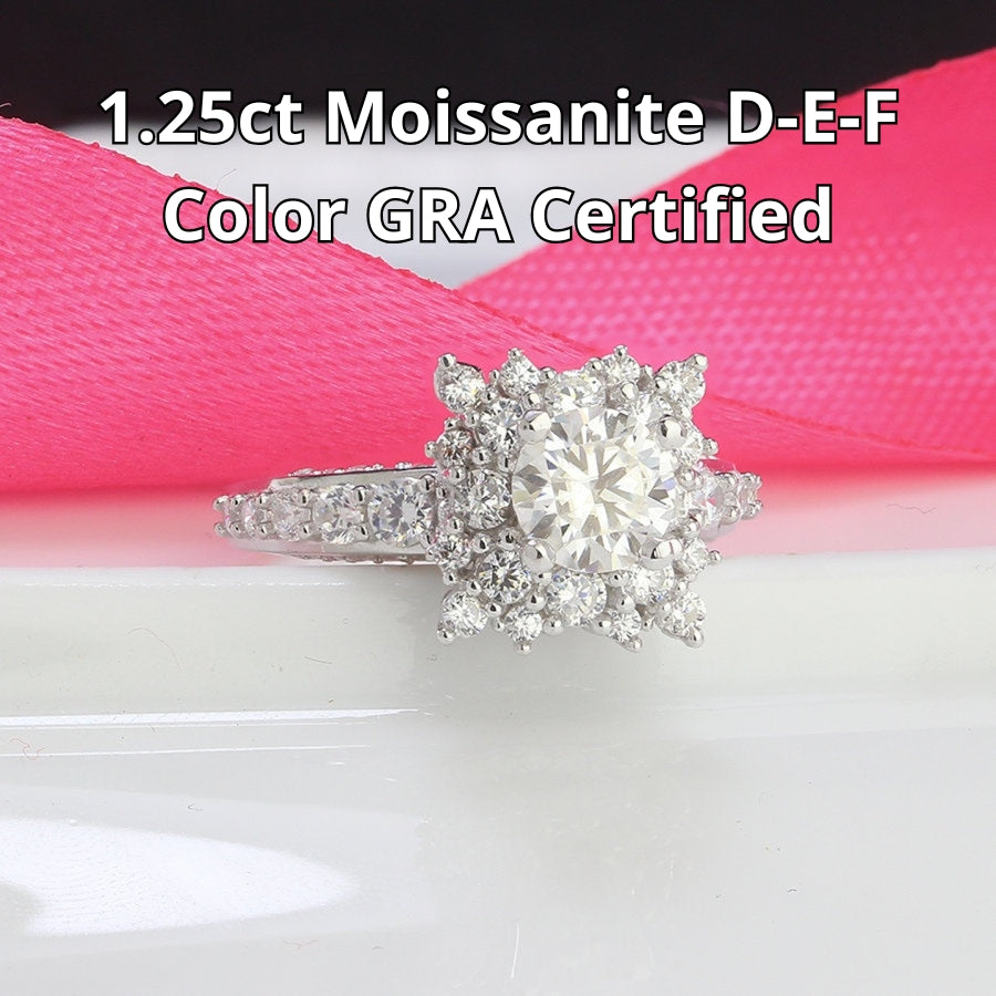 Vintage-inspired art deco design features brilliant round moissanite surrounded by sparkling halo accents on a delicate pavé band.