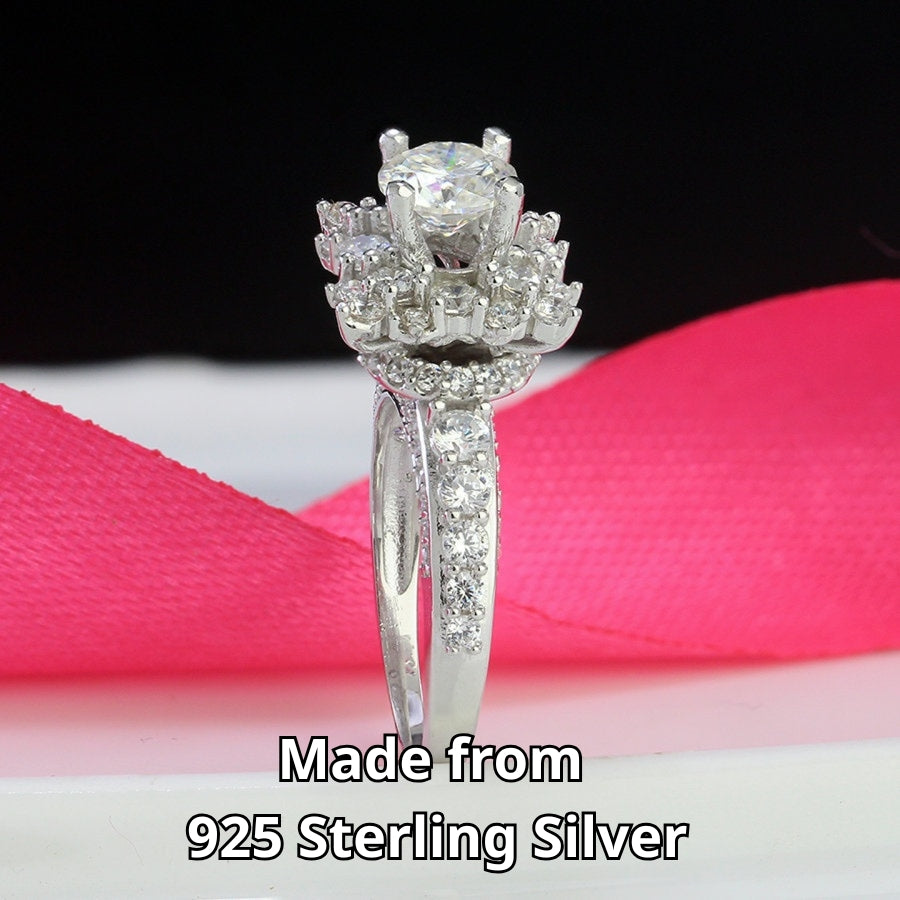 Vintage-inspired art deco design features brilliant round moissanite surrounded by sparkling halo accents on a delicate pavé band.