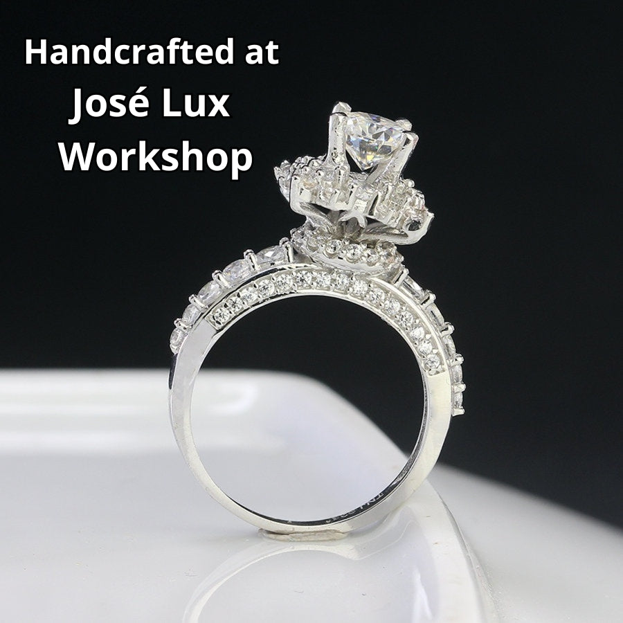 Vintage-inspired art deco design features brilliant round moissanite surrounded by sparkling halo accents on a delicate pavé band.