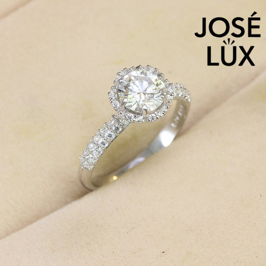 Classic halo design features brilliant moissanite centerpiece with shimmering accent stones creating timeless elegance on a refined silver setting.