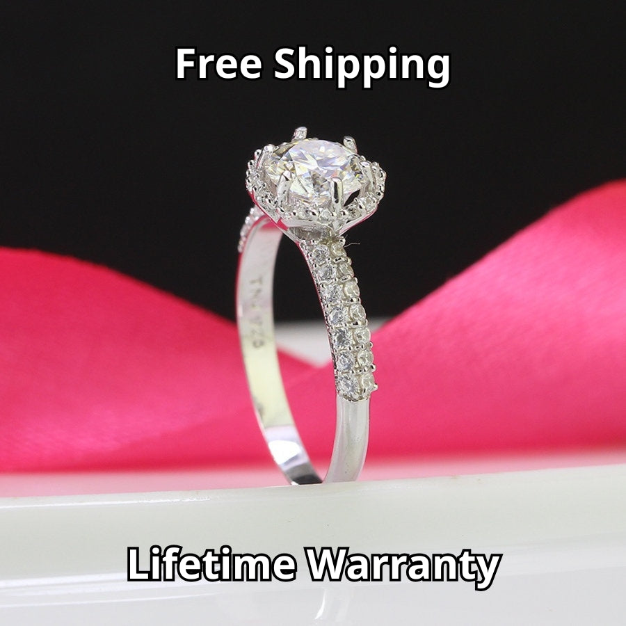 Classic halo design features brilliant moissanite centerpiece with shimmering accent stones creating timeless elegance on a refined silver setting.