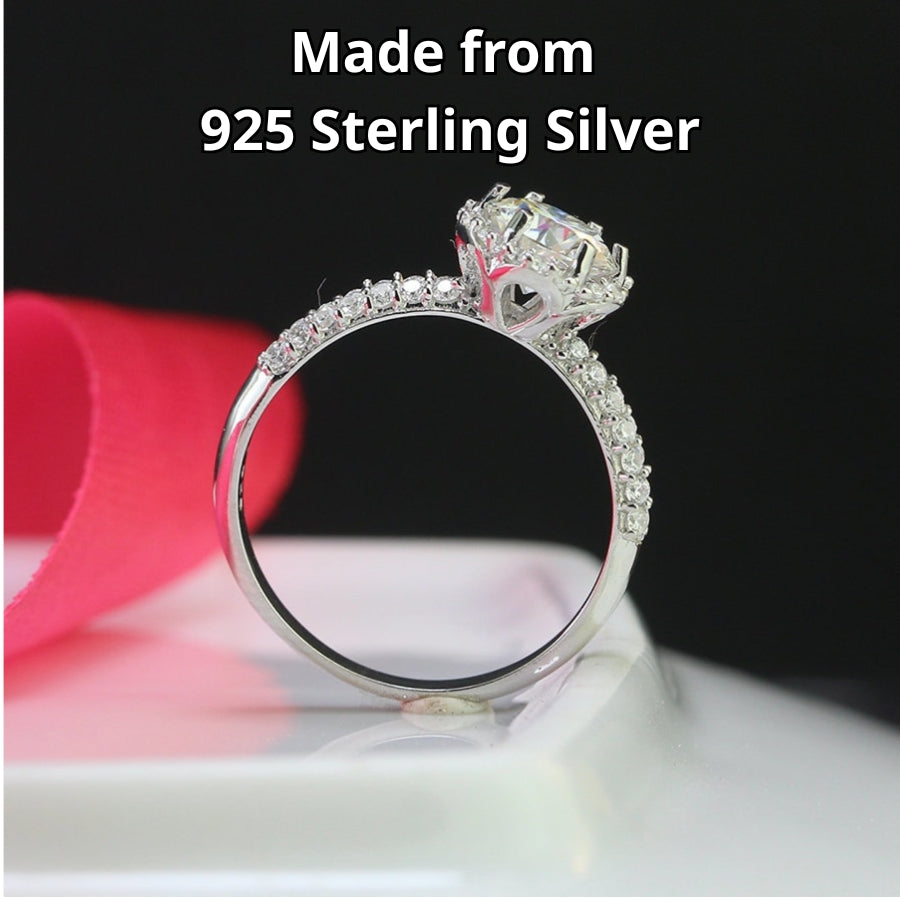 Classic halo design features brilliant moissanite centerpiece with shimmering accent stones creating timeless elegance on a refined silver setting.