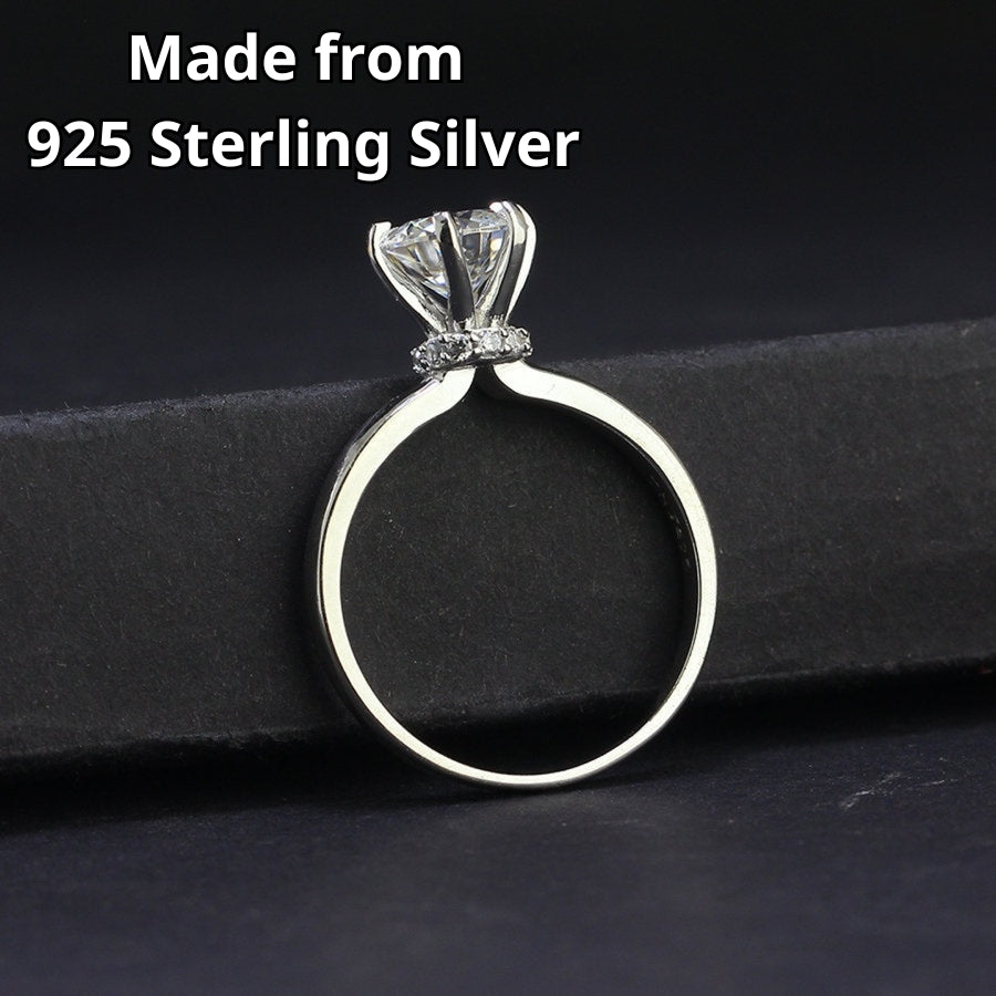 Traditional solitaire setting highlights brilliant round moissanite on a sleek silver band for timeless sophistication and everyday wearability.