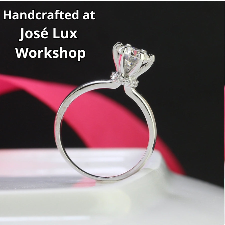 Traditional solitaire setting highlights brilliant round moissanite on a sleek silver band for timeless sophistication and everyday wearability.