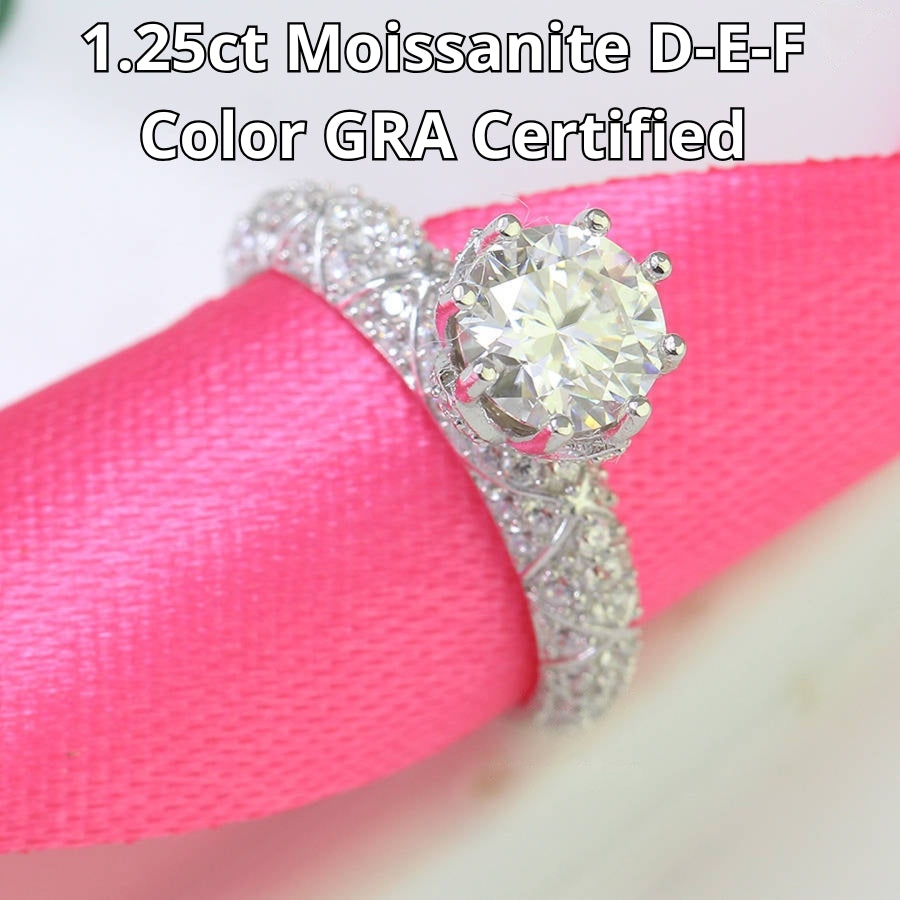 Elegant cathedral setting showcases brilliant round moissanite with sparkling pavé accents along the band for timeless sophistication and style.