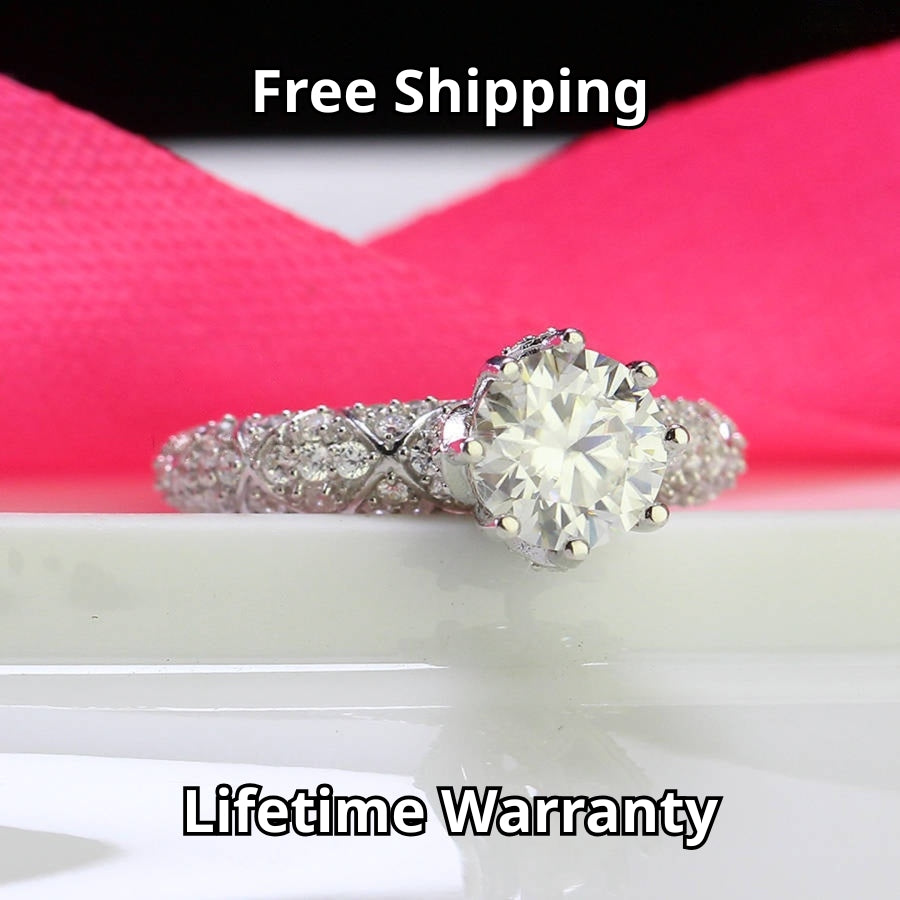 Elegant cathedral setting showcases brilliant round moissanite with sparkling pavé accents along the band for timeless sophistication and style.