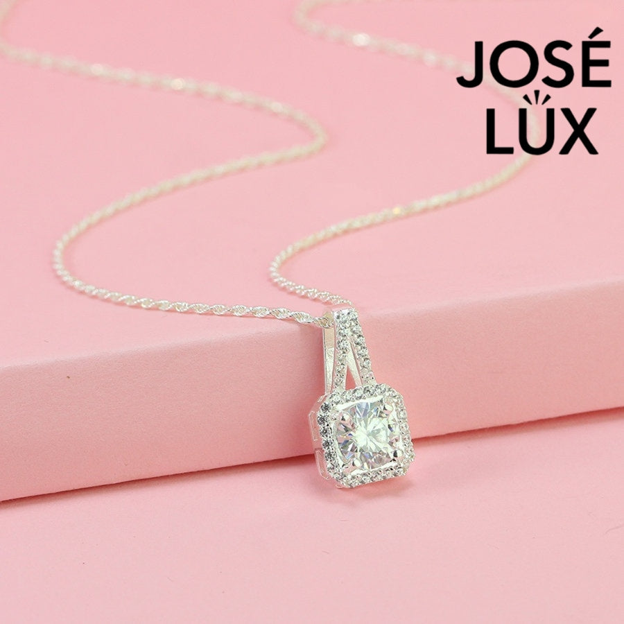 Sophisticated 1.2ct emerald cut moissanite halo pendant features geometric step-cut stone surrounded by sparkling pavé accents, elegantly crafted in lustrous sterling silver.