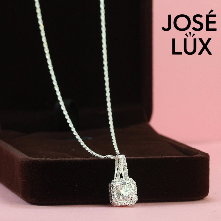 Sophisticated 1.2ct emerald cut moissanite halo pendant features geometric step-cut stone surrounded by sparkling pavé accents, elegantly crafted in lustrous sterling silver.