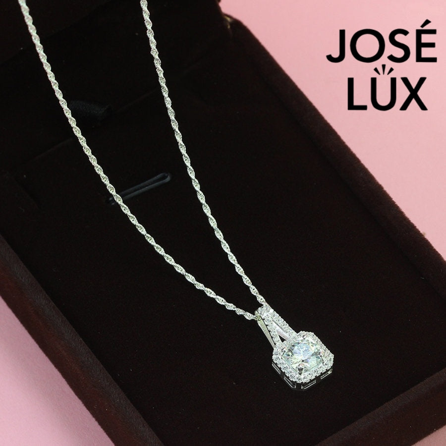 Sophisticated 1.2ct emerald cut moissanite halo pendant features geometric step-cut stone surrounded by sparkling pavé accents, elegantly crafted in lustrous sterling silver.