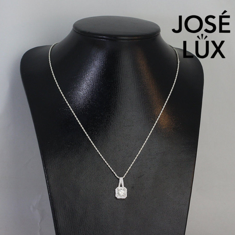 Sophisticated 1.2ct emerald cut moissanite halo pendant features geometric step-cut stone surrounded by sparkling pavé accents, elegantly crafted in lustrous sterling silver.