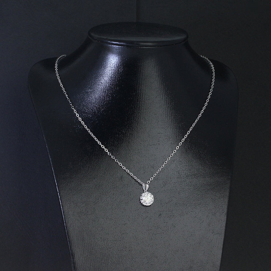 Romantic 1.2ct round moissanite heart halo pendant showcases brilliant center stone within pavé-set heart frame, lovingly handcrafted in gleaming sterling silver.