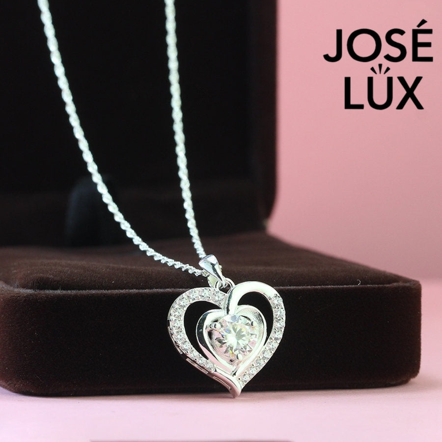 Romantic 1.2ct round moissanite heart halo pendant showcases brilliant center stone within pavé-set heart frame, lovingly handcrafted in gleaming sterling silver.