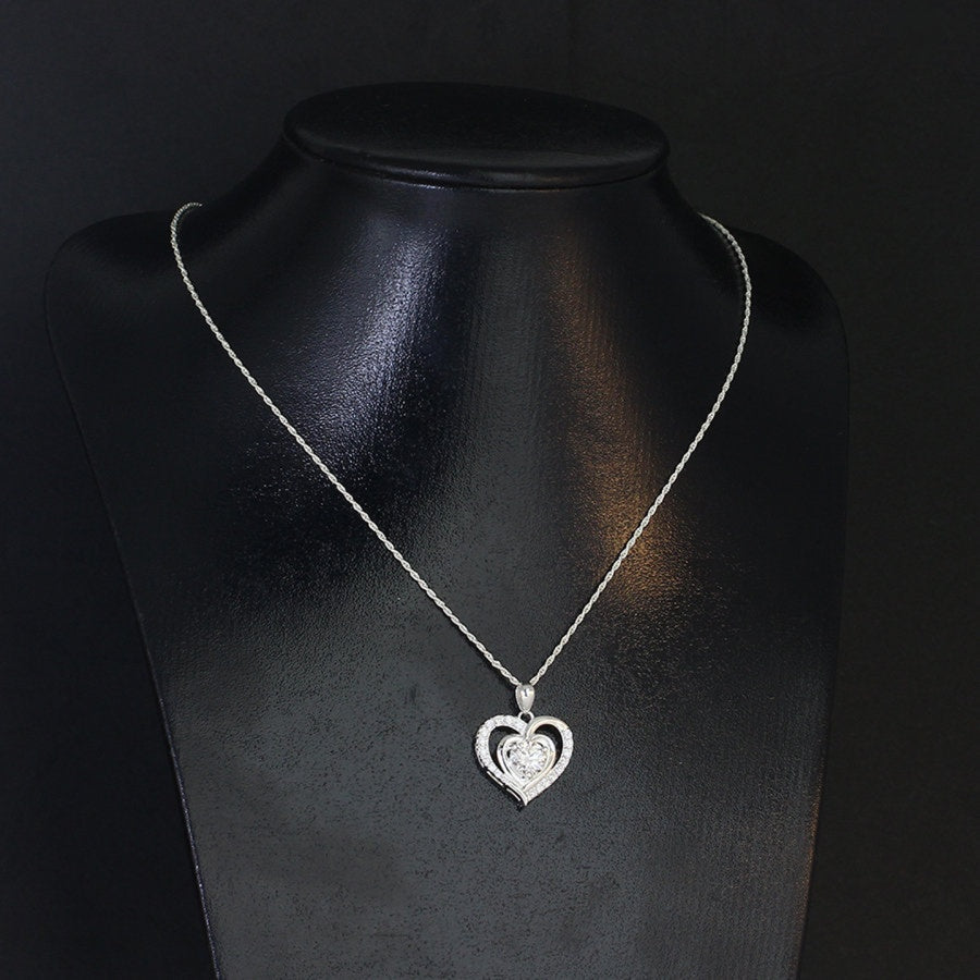 Romantic 1.2ct round moissanite heart halo pendant showcases brilliant center stone within pavé-set heart frame, lovingly handcrafted in gleaming sterling silver.