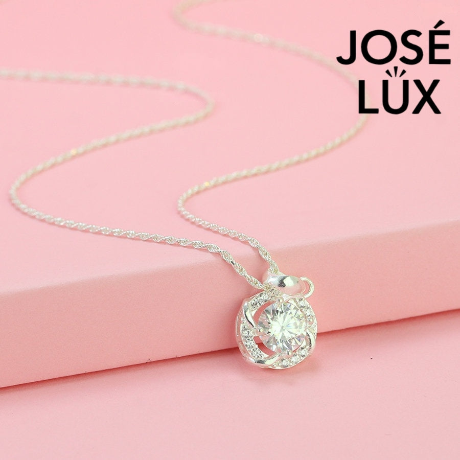 Intricate 1.2ct round moissanite twisted knot halo pendant showcases stunning center stone within pavé-accented interwoven design, artfully created in polished sterling silver.