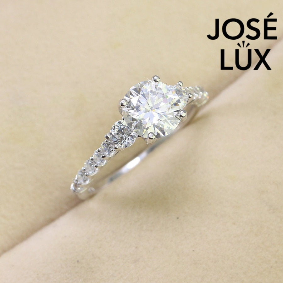 Brilliant 1.5ct moissanite center stone with sparkling side accents set in polished sterling silver creates timeless elegance for any occasion.