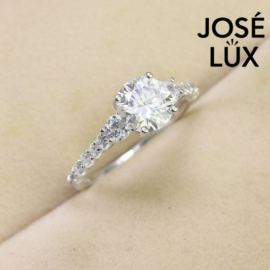 Brilliant 1.5ct moissanite center stone with sparkling side accents set in polished sterling silver creates timeless elegance for any occasion.