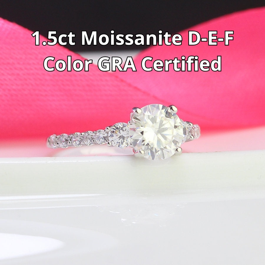 Brilliant 1.5ct moissanite center stone with sparkling side accents set in polished sterling silver creates timeless elegance for any occasion.