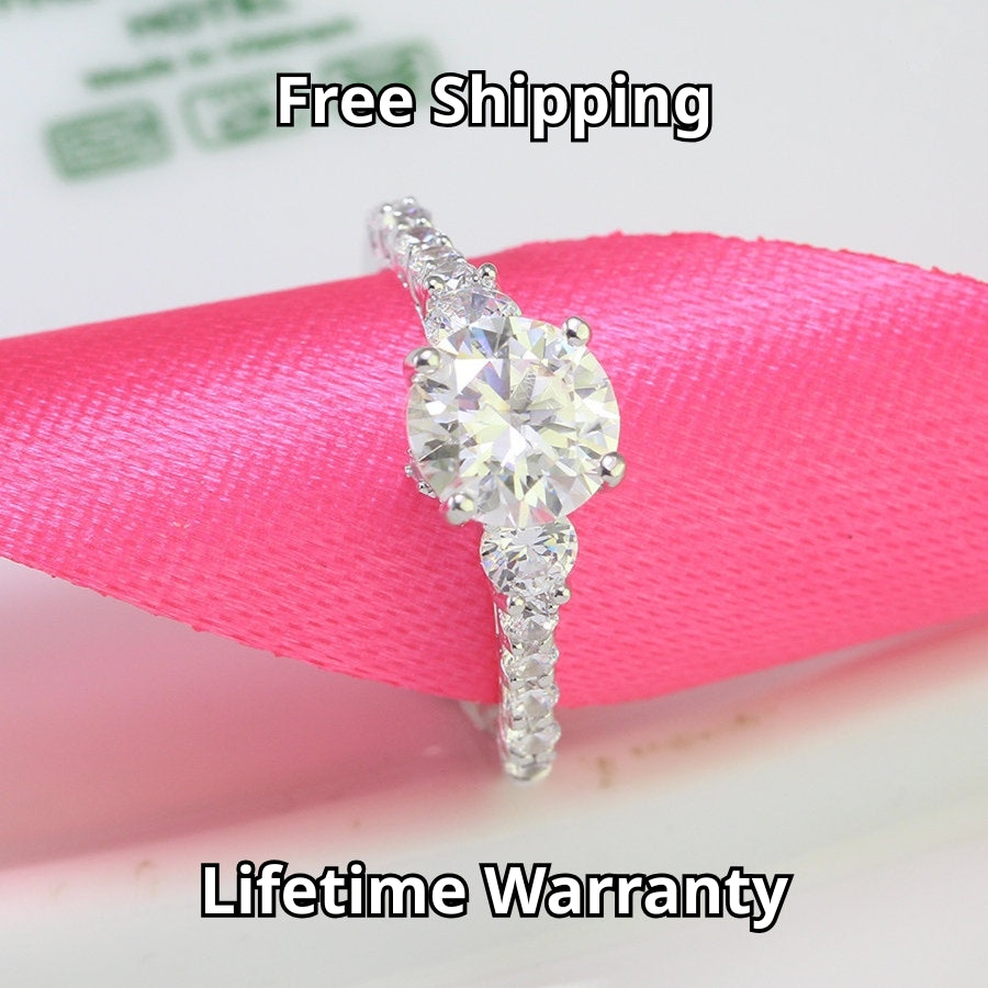 Brilliant 1.5ct moissanite center stone with sparkling side accents set in polished sterling silver creates timeless elegance for any occasion.