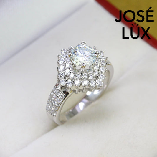 Brilliant round moissanite centerpiece enhanced by dual layers of sparkling accent stones with pavé detailing on the polished silver band.