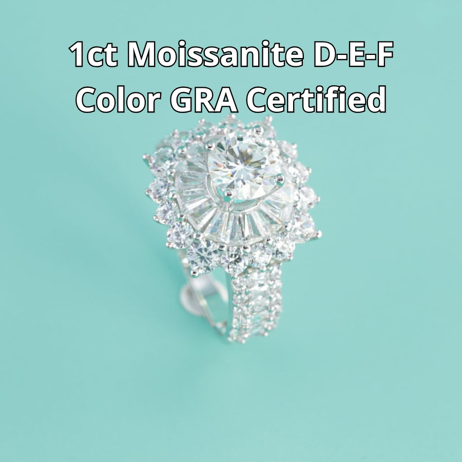 Stunning sunburst design features brilliant round moissanite surrounded by baguette and round accent stones with sparkling pavé band detailing.