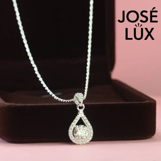Contemporary 1ct round moissanite open teardrop halo pendant showcases brilliant center stone within elegant wishbone frame, beautifully designed in sterling silver.