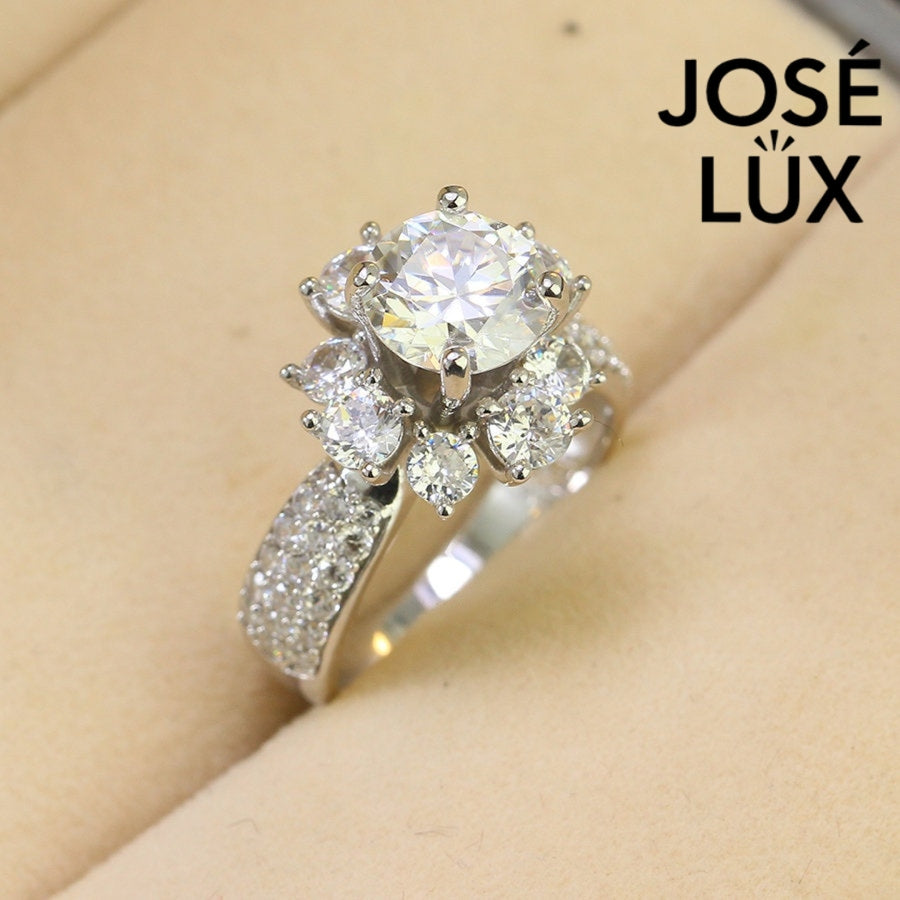 Stunning 2ct moissanite center stone surrounded by brilliant halo accents in a classic cluster design, beautifully crafted in sterling silver.