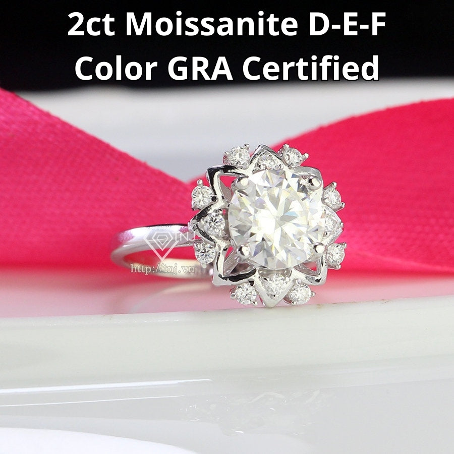 Stunning 2-carat moissanite center stone surrounded by sparkling accent stones in a classic flower halo setting crafted in polished silver.