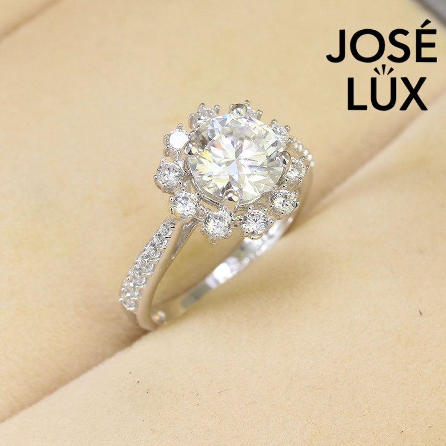 Elegant 2ct moissanite center stone surrounded by sparkling halo diamonds on a pavé silver band. Classic design perfect for special occasions and everyday elegance.