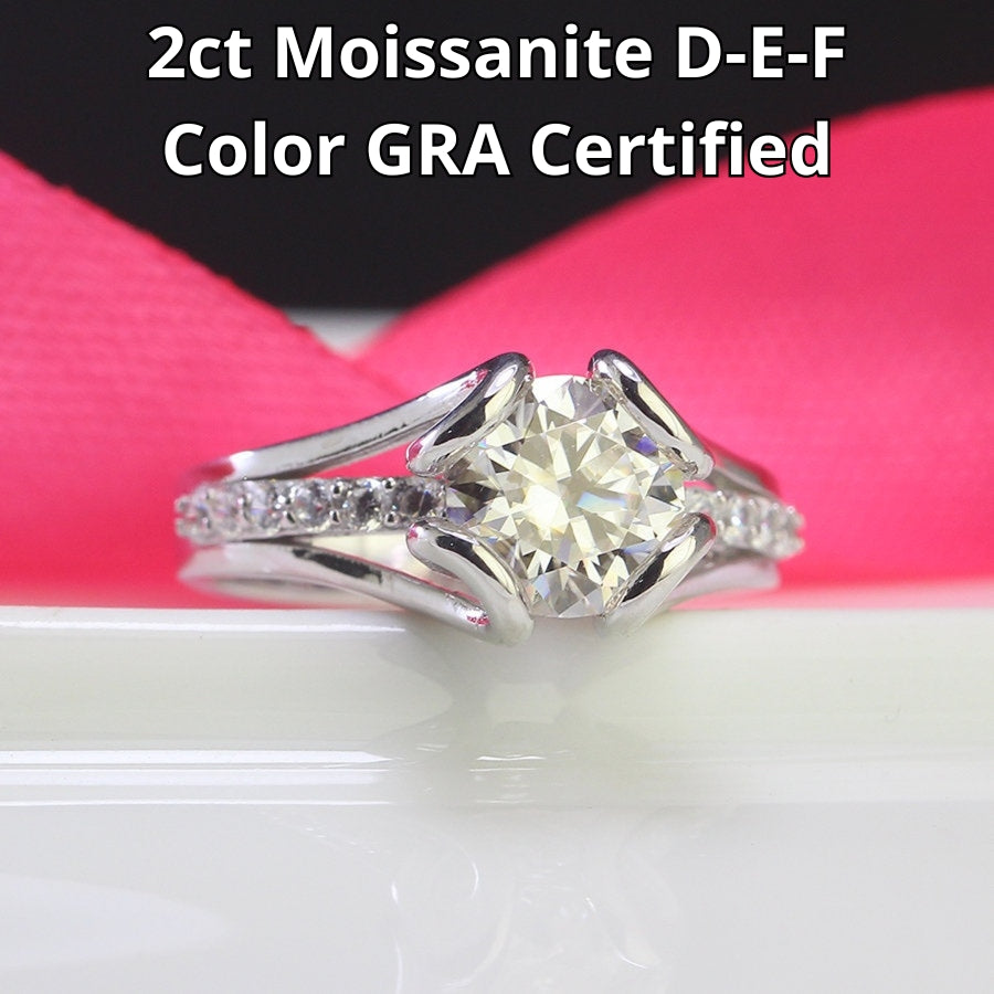 Elegant 2ct moissanite solitaire with split shank design and pavé accents, beautifully set in sterling silver for timeless sophistication.