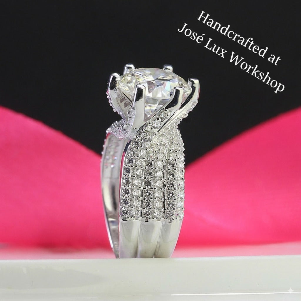 Brilliant 4ct round moissanite centerpiece showcased in sterling silver with sparkling pavé band. Classic design features exceptional fire and brilliance for timeless elegance.