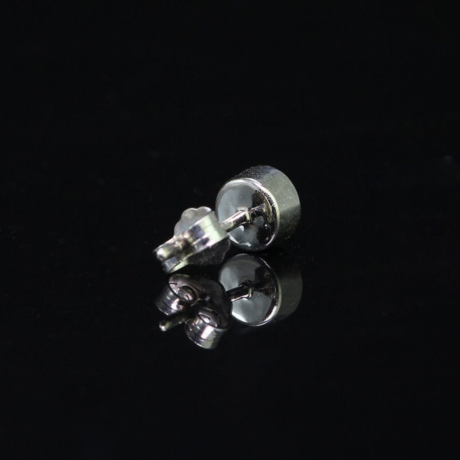 Sterling silver moissanite stud earring lying flat, showing bezel setting and post design for secure and stylish wear.