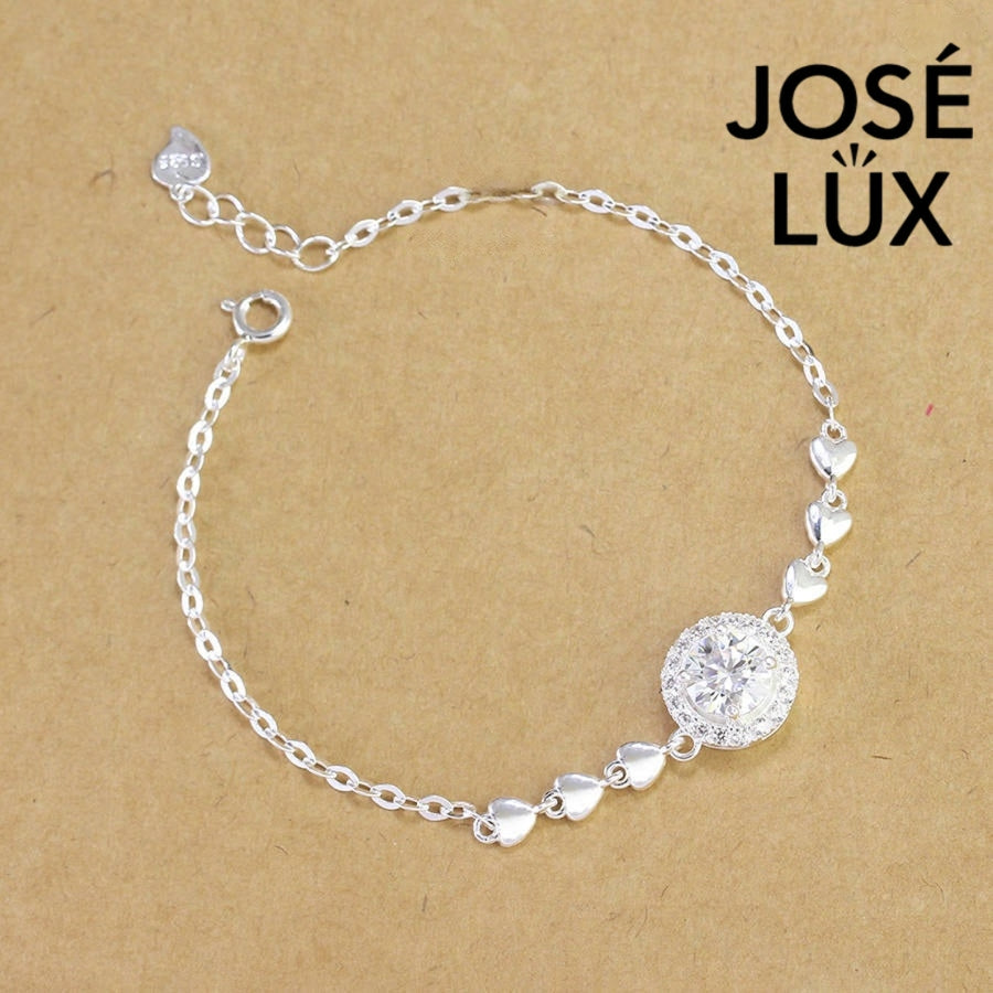 Cable chain halo moissanite bracelet in sterling silver features round brilliant centerpiece with heart accents weighing 1.0 carat on adjustable chain design.