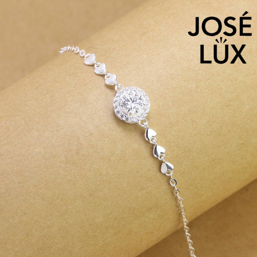 Cable chain halo moissanite bracelet in sterling silver features round brilliant centerpiece with heart accents weighing 1.0 carat on adjustable chain design.