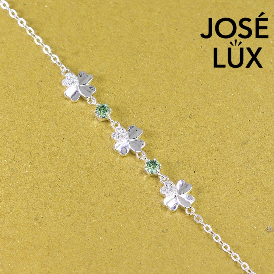 Clover link green moissanite bracelet in sterling silver displays three four-leaf motifs connected by brilliant green stones totaling 0.6 carats.