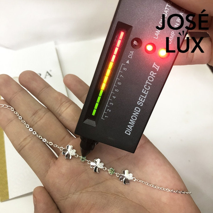 Clover link green moissanite bracelet in sterling silver displays three four-leaf motifs connected by brilliant green stones totaling 0.6 carats.