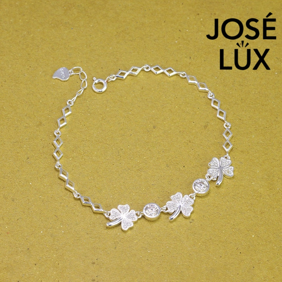 Four-leaf clover moissanite bracelet in sterling silver features three symbolic charms with two brilliant stones totaling 0.68 carats on geometric link chain.