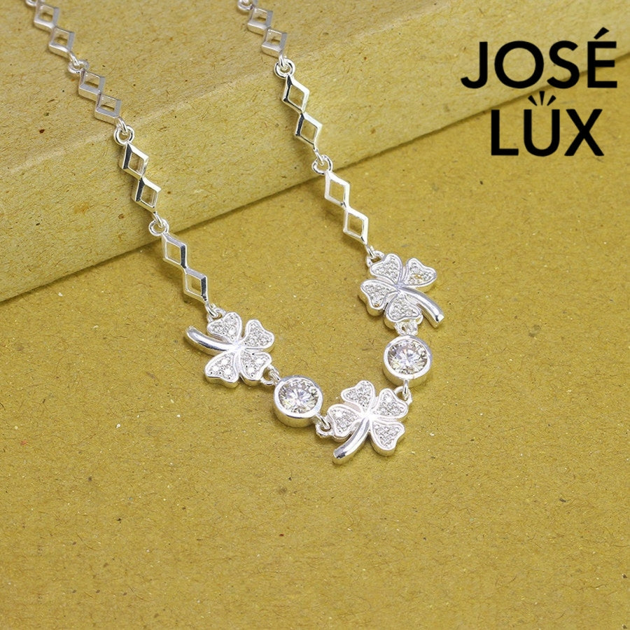 Four-leaf clover moissanite bracelet in sterling silver features three symbolic charms with two brilliant stones totaling 0.68 carats on geometric link chain.