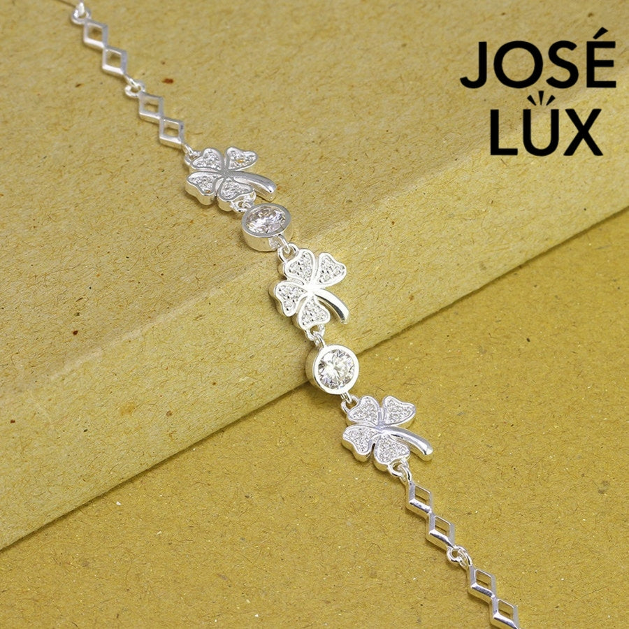 Four-leaf clover moissanite bracelet in sterling silver features three symbolic charms with two brilliant stones totaling 0.68 carats on geometric link chain.