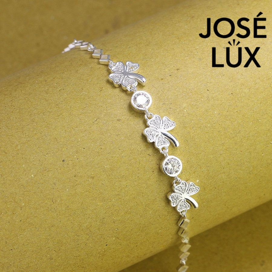 Four-leaf clover moissanite bracelet in sterling silver features three symbolic charms with two brilliant stones totaling 0.68 carats on geometric link chain.