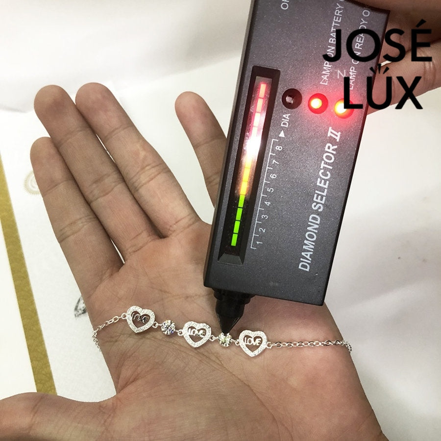 Love script heart station moissanite bracelet in sterling silver showcases three engraved heart charms with brilliant stones totaling 1.02 carats on cable chain.