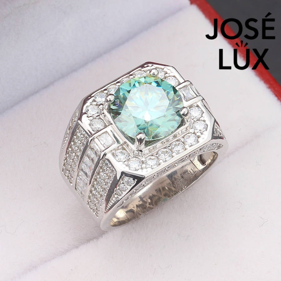 Substantial sterling silver men's ring featuring a 4-carat round green moissanite encircled by a cushion-shaped halo. Wide band with alternating rows of round and baguette stones creates impressive depth and dimension.